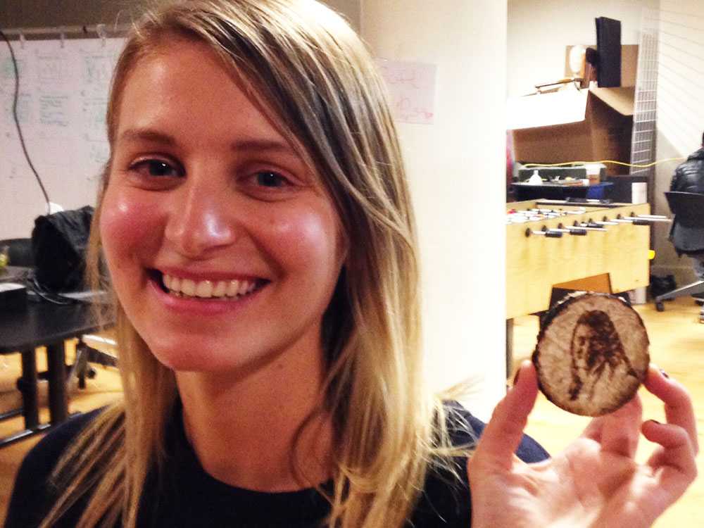 Rebecca Ricks holding a piece of mushroom with her face etched on it